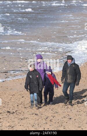 Eine Familie und ihr Hund beim Spaziergang entlang den Fistral Beach in Newquay in Cornwall. Stockfoto