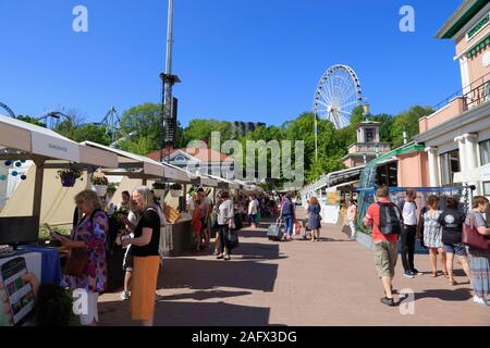 Menschen gehen vorbei und Shop auf Marktständen im Vergnügungspark Liseberg in Göteborg, Schweden. Stockfoto