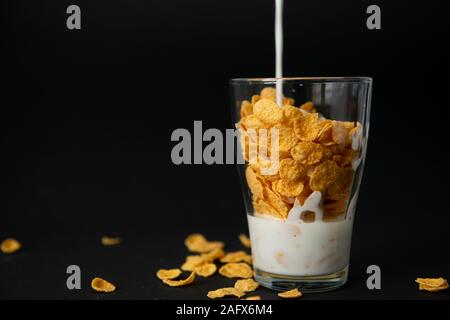 Cornflakes in transparentem Glas auf schwarzem Hintergrund Stockfoto