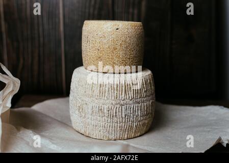 Verschiedenen hausgemachten Käse auf einem dunklen Hintergrund. Stücke und Käse Staats kravot, Manchego, Paramezan. Ziege und Kuh Käse auf Backpapier. Uhr Stockfoto
