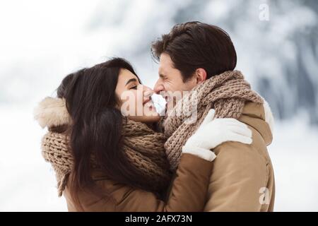 Cute Liebhaber Reiben ihre Nasen umarmen In Snowy Park Stockfoto