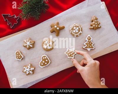 Frau Hände halten Lebkuchen Stern. Schöne Weihnachten Hintergrund mit Lebkuchen Männer, Weihnachtsbäume und Schneeflocken, Stern, mit Pinien, Hintergrund Stockfoto