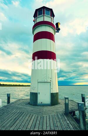 Romantischer Abend Spaziergang auf Holz- Mole zu Leuchtturm am Neusiedler See (Podersdorf am See) bei Sonnenuntergang, Burgenland, Österreich Stockfoto