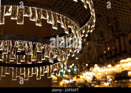 Kristallglas Kronleuchter mit dünnen und transparenten Platten, abstrakte Beleuchtung, warmes Licht Hintergrund. Großer Kronleuchter mit Crystal rectangula Stockfoto