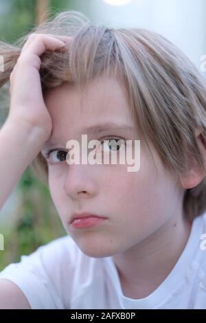 Porträt einer Schule - alter Junge mit seiner Hand auf seinen Kopf, mit Traurigkeit in seinen Augen Stockfoto