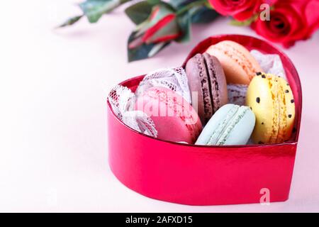 Bunte französische Macarons in einem Herzförmigen Geschenkbox auf rosa Hintergrund traditioanal Dessert in Frankreich, Valentinstag Konzept Stockfoto
