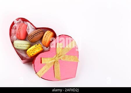 Bunte französische Macarons in einem Herzförmigen Geschenkbox auf rosa Hintergrund traditioanal Dessert in Frankreich, Valentinstag Konzept Stockfoto