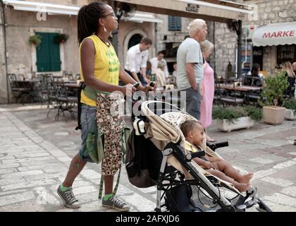 Kotor, Montenegro, 22. September 2019: Frau mit Baby, die in der Altstadt von Kotor die Straße hinunter läuft Stockfoto