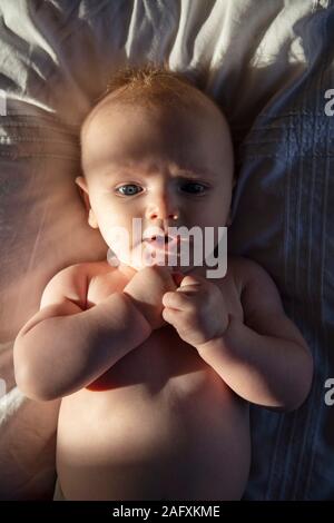 Ein drei Monate altes Baby boy Verlegung auf einer weichen Decke mit dramatischen Abendsonne Stockfoto