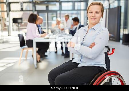 Zuversichtlich Geschäftsfrau im Rollstuhl in der Begegnung mit Team im Hintergrund Stockfoto