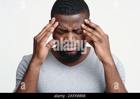 Schwarze Kerl in Kopfschmerzen, seine Schläfen berühren Stockfoto