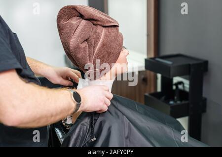 Frau mit einem Handtuch auf dem Kopf nach dem Waschen den Kopf oder vor dem Haarschnitt im Beauty Salon. Stockfoto