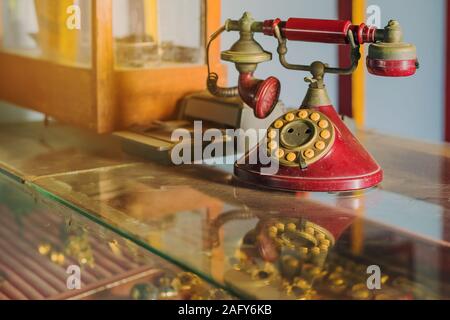 Eine rote telehones Drehgeber mit Staub und Kratzern und Kreditkarte Maschine in den alten Zeiten auf einer Glasvitrine in einem alten Gold shop in so platziert Stockfoto