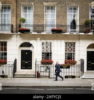 Ein traditionelles Londoner georgianische Stadthaus in Bloomsbury mit einem elegant gekleidete Geschäftsmann vorbei Reden auf seinem mobilen Stockfoto