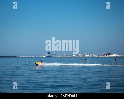 Russland, Sotschi 05.10.2019. Gruppe von Leuten auf den Segelfliegen surfen mit Paddel im Meer und Jet Ski Stockfoto