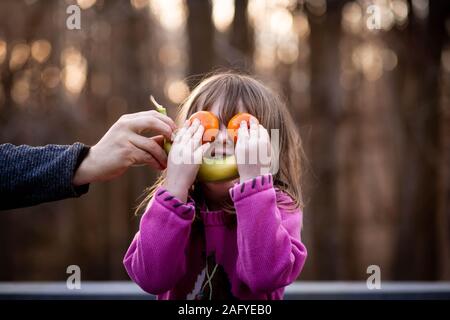 Junge Mädchen stellt Obst auf dem Gesicht silly nach außen zu machen Stockfoto