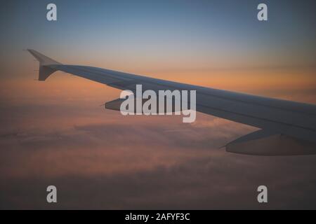 Die Tragfläche eines Flugzeugs in einem orange Sonnenuntergang Himmel Stockfoto