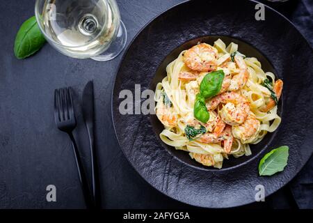 Italienische Pasta fettuccine in eine cremige Soße mit Garnelen auf einer schwarzen Platte, Ansicht von oben Stockfoto