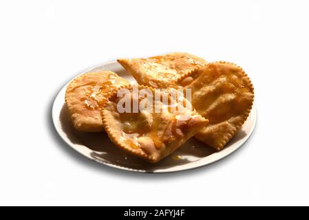 Knusprige Honig garniert kretischen traditionellen lokalen süße Leckerei Mizithropites auf Weiß isoliert. Hausgemachte frittierte Gebäck mit Hüttenkäse, cinnam Stockfoto