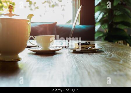 Teekanne mit Tasse und blueberry Käse Kuchen auf Holztisch. Stockfoto