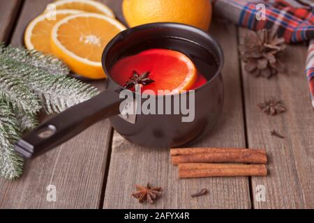 Alte Metall pan Pot an leckeren Glühwein mit Topf mit Gewürzen und Orange Früchte und Geschenkboxen auf hölzernen Tisch. Stockfoto