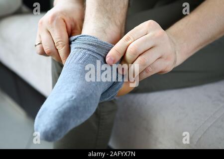 Mann zu Hause am Morgen bringt graue Socken auf seinem Bein Stockfoto