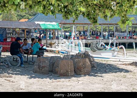 Gruppe von Männern im Schatten sitzen unter Baumkrone beobachten, Hähne in Körben geschlossen Stockfoto