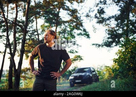 Schwarz Auto hinter sich. Porträt der Menschen, die in den Wald und Natur steht Stockfoto