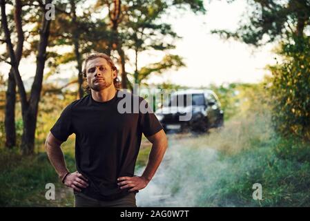 Schwarz Auto hinter sich. Porträt der Menschen, die in den Wald und Natur steht Stockfoto