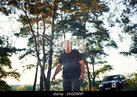 Schwarz Auto hinter sich. Porträt der Menschen, die in den Wald und Natur steht Stockfoto