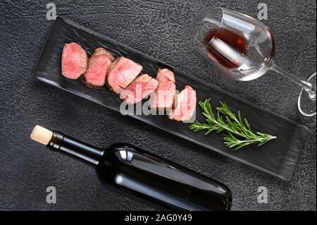 Flasche Rotwein mit in Scheiben geschnittenen Filet Mignon: Ansicht von oben Stockfoto