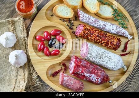 Sortiment von Salami mit Häppchen auf hölzernen Hintergrund: Ansicht von oben Stockfoto