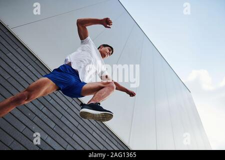 In die Luft. Junge sport Mann tun Parkour in der Stadt am sonnigen Tag Stockfoto