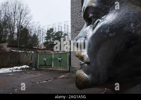 Büste von Wladimir Iljitsch Lenin am Eingang in den Bereich der Duga-1 (auch als ANDR-1 oder Russischen Specht) in der Nähe von Tschernobyl innerhalb der Sperrzone von Tschernobyl. Im Hintergrund ist der Duga-1-Array gesehen. Der E8288 ist eine Sowjetische gebaut, über dem Horizont Radar für interkontinentale ballistische Rakete startet. Die Bauarbeiten begannen im März 1972. Die ersten Sendungen aus diesem Betrieb wurden auf den 4. Juli 1976 lesen. Am Morgen des 26. April 1986 die Operationen der Radar gestoppt. Sperrzone von Tschernobyl, Invankiv Rajon, Oblast Kiew, Ukraine, Osteuropa Stockfoto