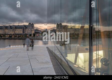 OSLO, Norwegen - 21. Juli 2019: Stadt und der Himmel spiegelt sich auf Opera Theater Glasfassade, nach Einbruch der Dunkelheit trübe hellen Sommer Licht am 21. Juli 2019 in Osl Schuß Stockfoto