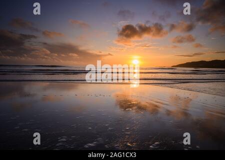 Charmouth, Dorset, Großbritannien. 17. Dezember 2019. UK Wetter: Schöne Farben in den Himmel bei Sonnenuntergang in den nassen Sand bei Ebbe wider, wie die Sonne über dem Horizont in der Nähe von charmouth am Ende des Tages den Winter setzt. Credit: Celia McMahon/Alamy Leben Nachrichten. Stockfoto