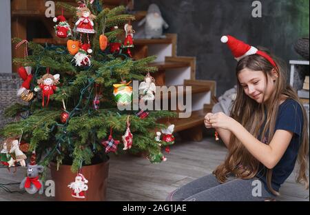 Ein junges Mädchen ziert eine kleine, natürliche Weihnachtsbaum zu Hause Stockfoto