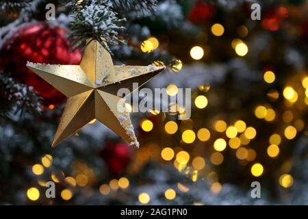 Weihnachten Stern auf einer tannenzweigen auf festliche Golden Lights Hintergrund zu erhalten, auf Nacht, Beleuchtung. Neues Jahr Baum mit Dekorationen, Magie einer Ferienwohnung Stockfoto