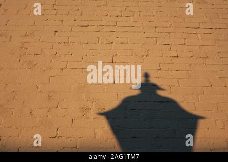 Der Schatten eines einzelnen Straßenlaterne cast auf eine Wand. Stockfoto