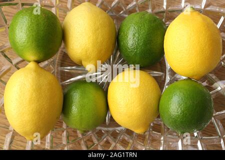 Abwechselnd Zitronen und Limetten in einer Glasschale Stockfoto