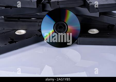 Eine DVD vor videobänder und auf Weiß isoliert. Passieren Sie den Inhalt Ihrer Videokassetten auf DVD. Stockfoto