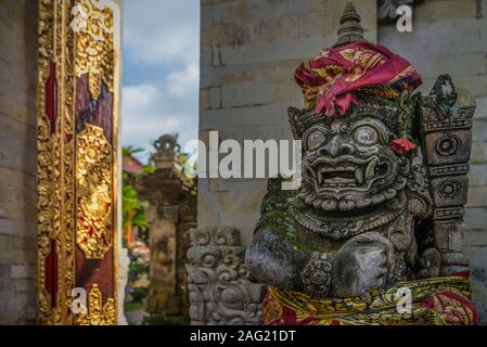 Traditionelle Statue am Eingang des Ubud Royal Palace, mit goldenen Tür, auf Teilweise sonnigen Nachmittag, in Ubud, Indonesien Stockfoto