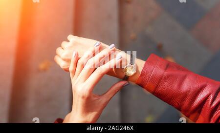 Street Style Fashion details., young Fashion Blogger trägt eine Jacke und eine analoge Armbanduhr. stilvolle Frau, die Zeit der Überprüfung auf ihre Uhr. Herbst Herbst Jahreszeit. Stockfoto