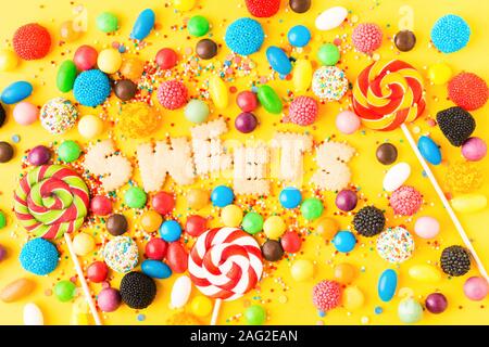 Viele verschiedene bunte ungesund süßen Süßigkeiten. Mix Desserts für Urlaub. Süße Tabelle für Geburtstag auf gelben Hintergrund. Flach. Candy Bar Stockfoto