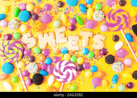 Viele verschiedene bunte ungesund süßen Süßigkeiten. Mix Desserts für Urlaub. Süße Tabelle für Geburtstag auf gelben Hintergrund. Flach Stockfoto