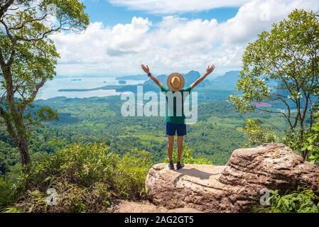 Stock Bild: junger Mann mit Hände nach oben gestreckt steht auf einem Felsen hoch in den Bergen. Konzept der Erfolg, gesund Leben, Harmonie, Reisen im Urlaub. Stockfoto