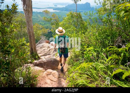 Traveler Wanderungen entlang der felsigen Weg in tropischen Wald mit atemberaubender Landschaft und das Meer weit unten am Horizont, in Krabi, Thailand. Khao Ngon Nak Naturlehrpfad Stockfoto