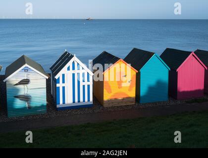 Herne Bay, Großbritannien - 11.Dezember 2019 bunte Dekoration am Strand Hütten entlang der Küste bei Herne Bay, Kent an einem strahlenden Wintertag. Die Überreste der Pier kann Stockfoto