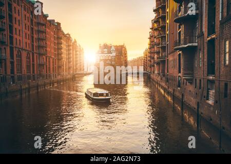 Hamburg Speicherstadt in golgen Stunde Sonnenuntergang beleuchtet. Wasser schloss Palast und touristische besuchen Bootsfahrt in Fluss. Alte Lager port, Deutschland, Europa Stockfoto