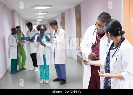 Medizinische Studenten, Praktikanten. Junge Ärzte, gemischten Rennen, auf dem Flur des Krankenhauses, Beratung. X-ray Bilder von Patienten untersucht, medizinische Pr Stockfoto